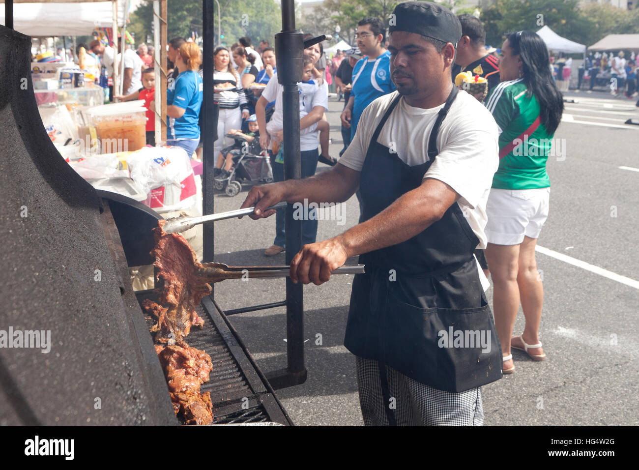 Latino man la cuisson des viandes au barbecue grille en un événement en plein air - USA Banque D'Images