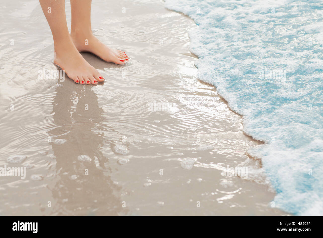 Pieds de femme debout en surf à la plage Banque D'Images