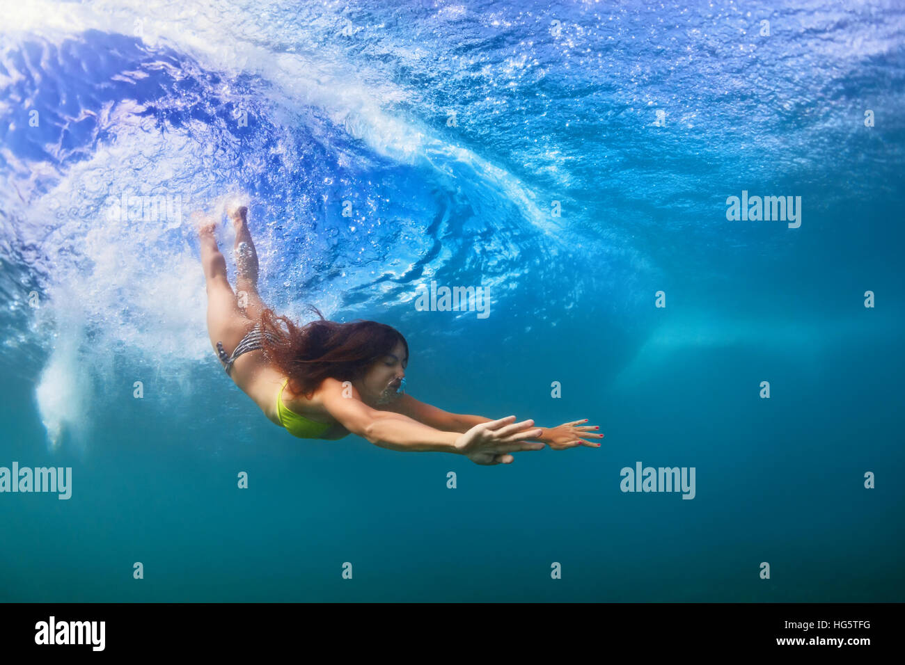 Jeune fille sportive en bikini en action. Fit woman nager sous l'eau, plonger sous la houle à l'effraction. Mode de vie sain. Sports nautiques, surf extrême Banque D'Images