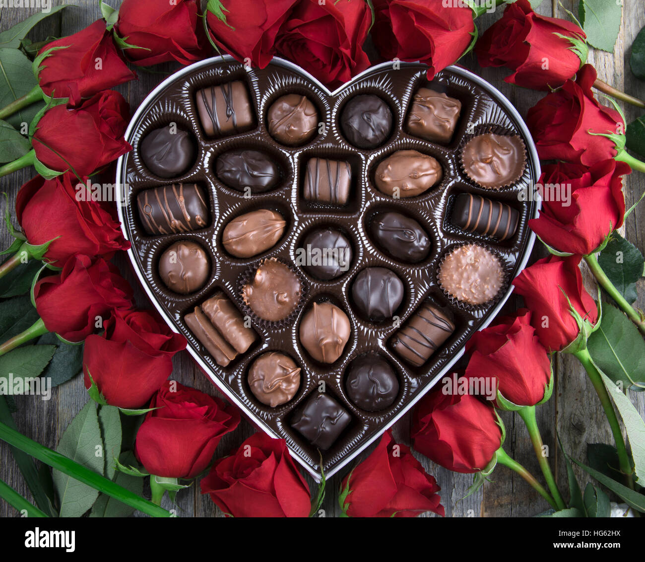 Boîte de chocolats en forme de coeur entouré de roses. Banque D'Images
