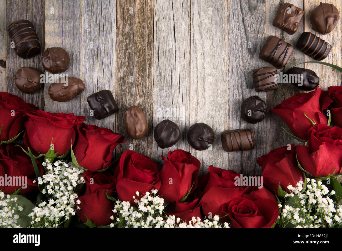 Roses rouges, gypsophile, et des chocolats sur fond de bois avec l'exemplaire de l'espace. Banque D'Images