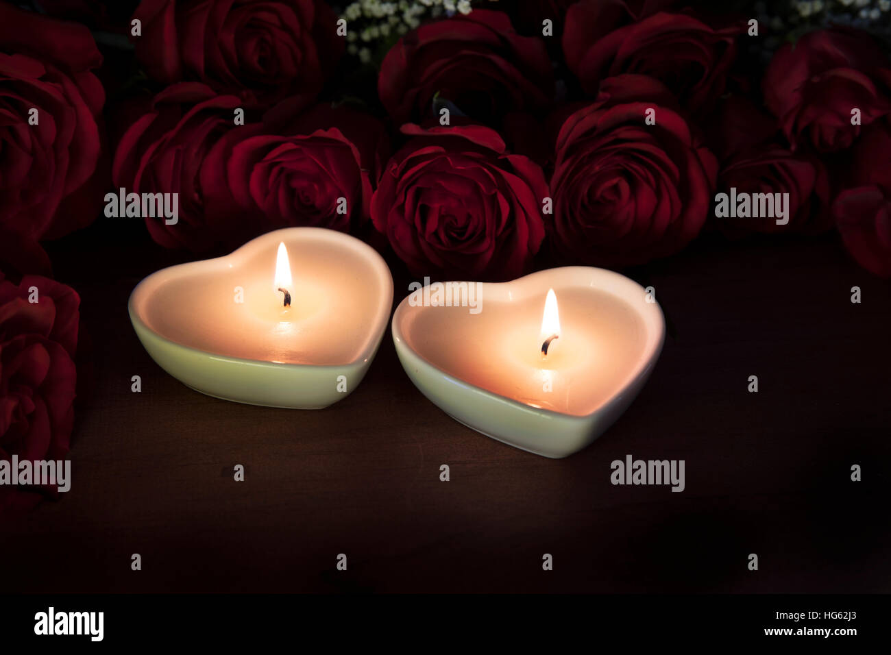 Deux bougies en forme de coeur avec des roses rouges. Banque D'Images