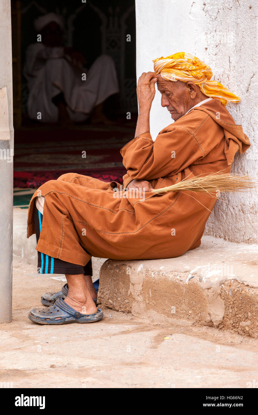 Elkhorbat, Maroc. L'homme se reposant à l'extérieur Entrée d'une mosquée. Banque D'Images