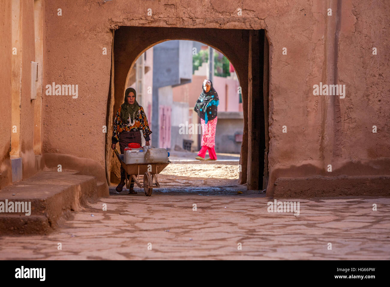 Ksar Elkhorbat, Maroc. Femme apportant l'eau dans sa brouette dans la Casbah. Banque D'Images