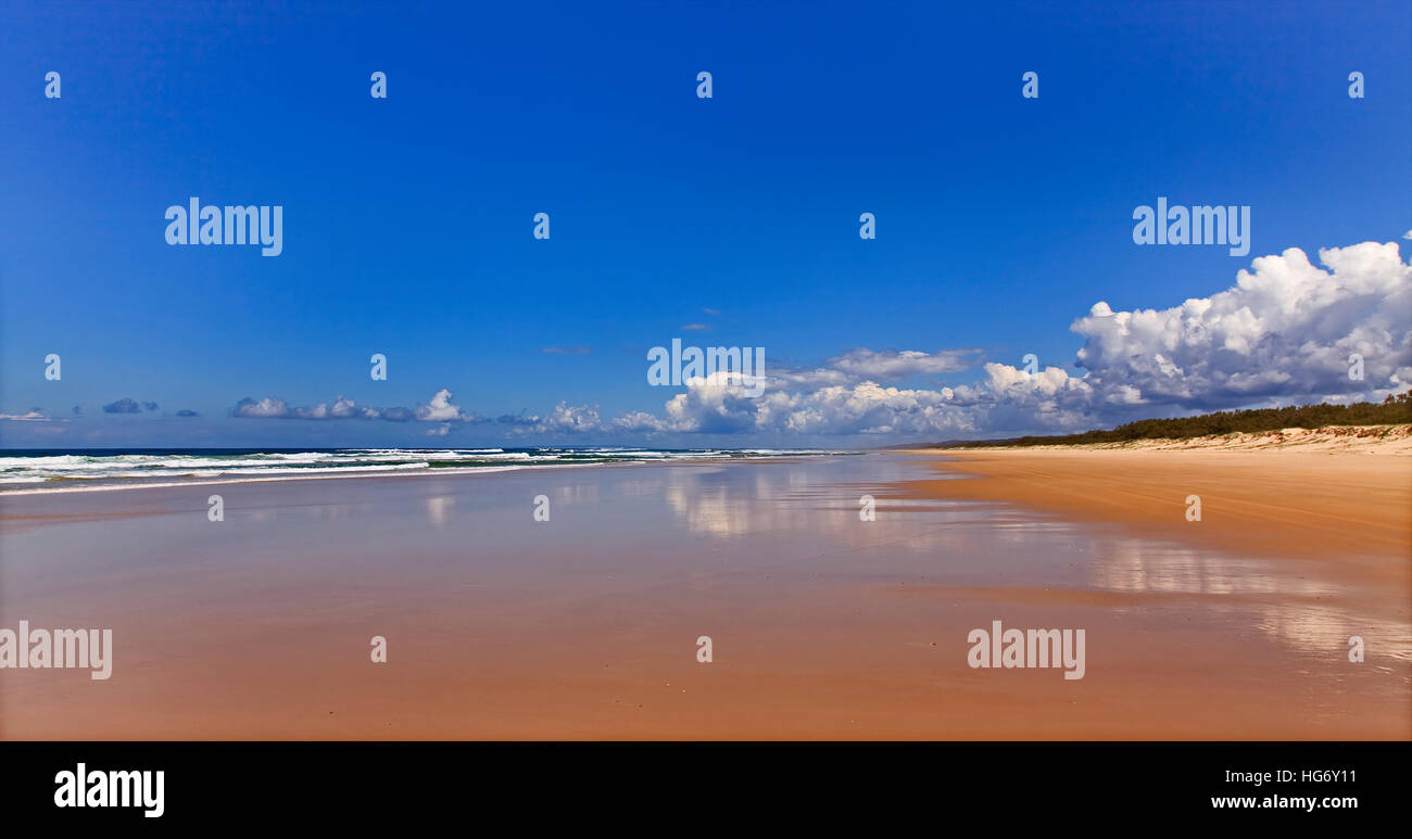 Large panorama de vide 75 miles beach sur la côte pacifique de l'île de Fraser dans le Queensland, Australie. L'été ensoleillé avec nuages de jour en milieu humide du sable propre à Banque D'Images