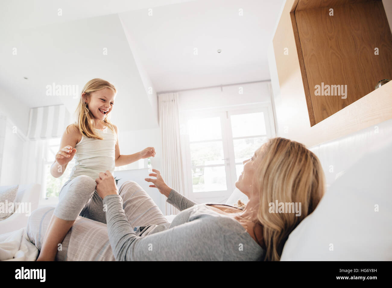 Tourné à l'intérieur de la petite fille jouant avec sa mère sur le lit. Mère et fille jouer dans la chambre. Banque D'Images