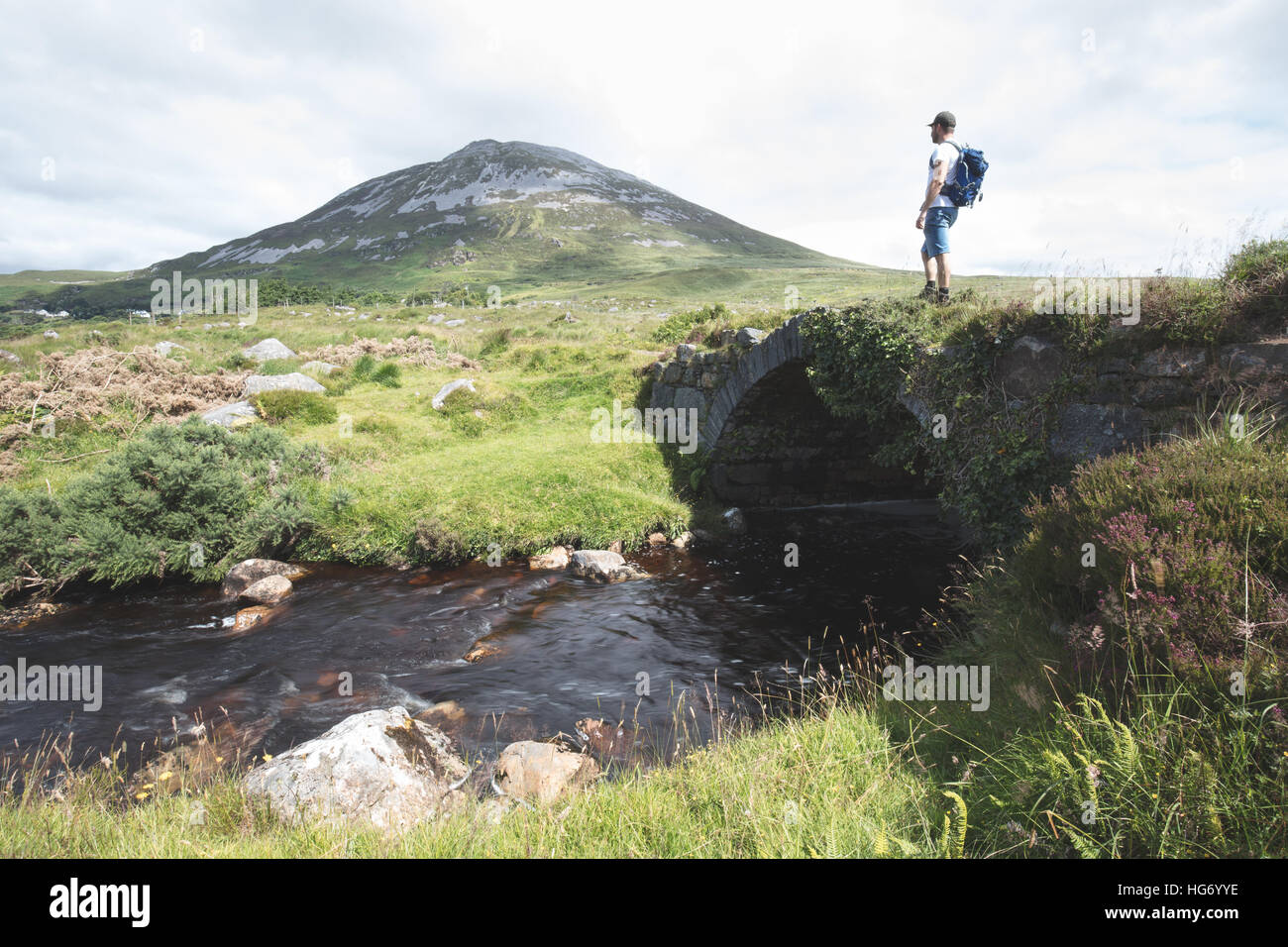 Lone walker se tenait sur un vieux pont dans le Glen empoisonné avec une vue sur le Mont Errigal. Le Glenveagh National Park, comté de Donegal, J Banque D'Images
