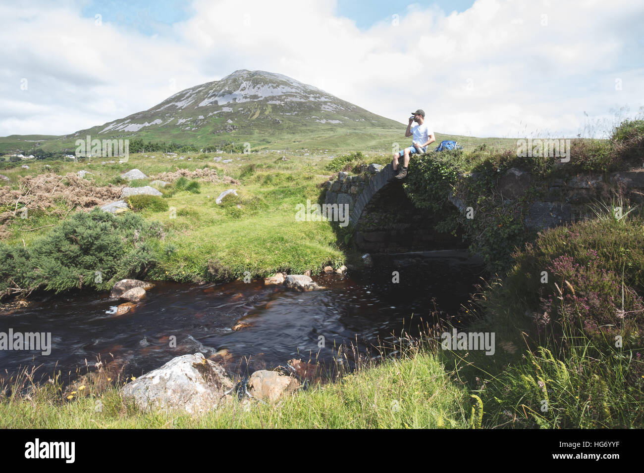 Lone walker se tenait sur un vieux pont dans le Glen empoisonné avec une vue sur le Mont Errigal. Le Glenveagh National Park, comté de Donegal, J Banque D'Images