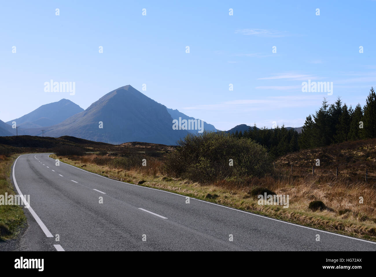 Montagnes lointaines contre ciel bleu avec route vide au premier plan. Banque D'Images