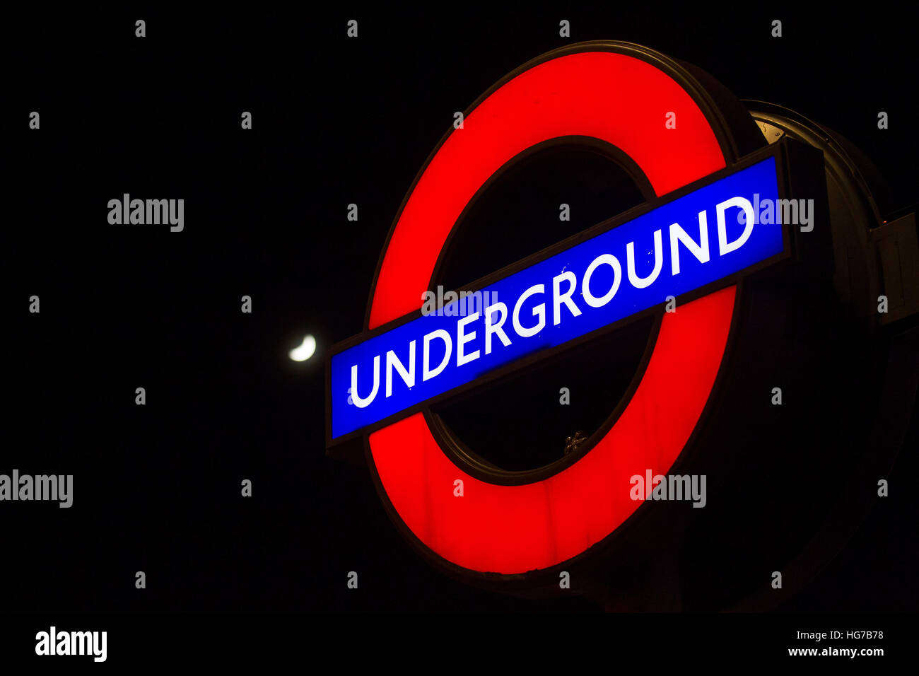 London Underground tube lumineux cocarde signe dans la nuit avec la lune Banque D'Images