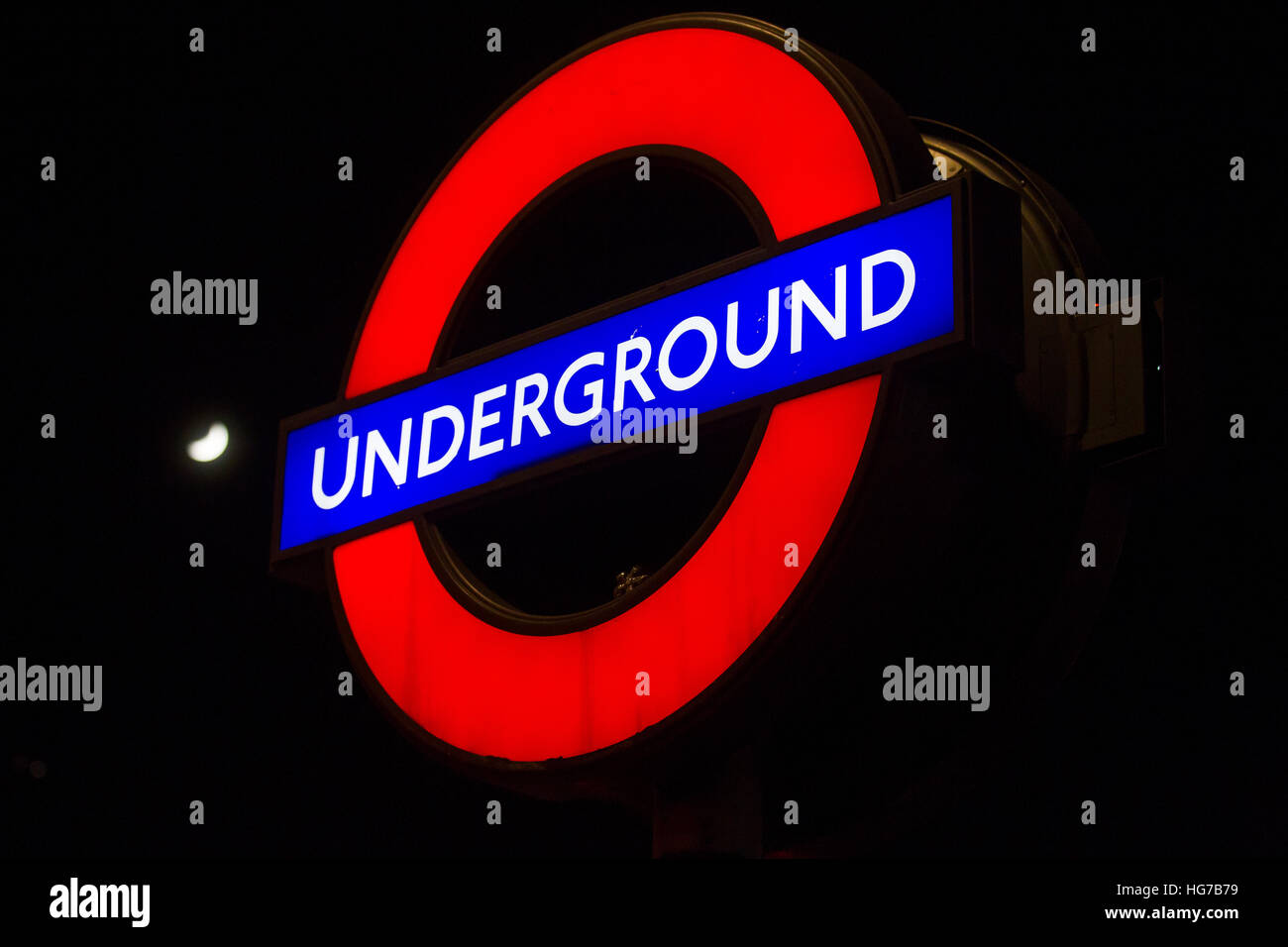 London Underground tube lumineux cocarde signe dans la nuit avec la lune Banque D'Images