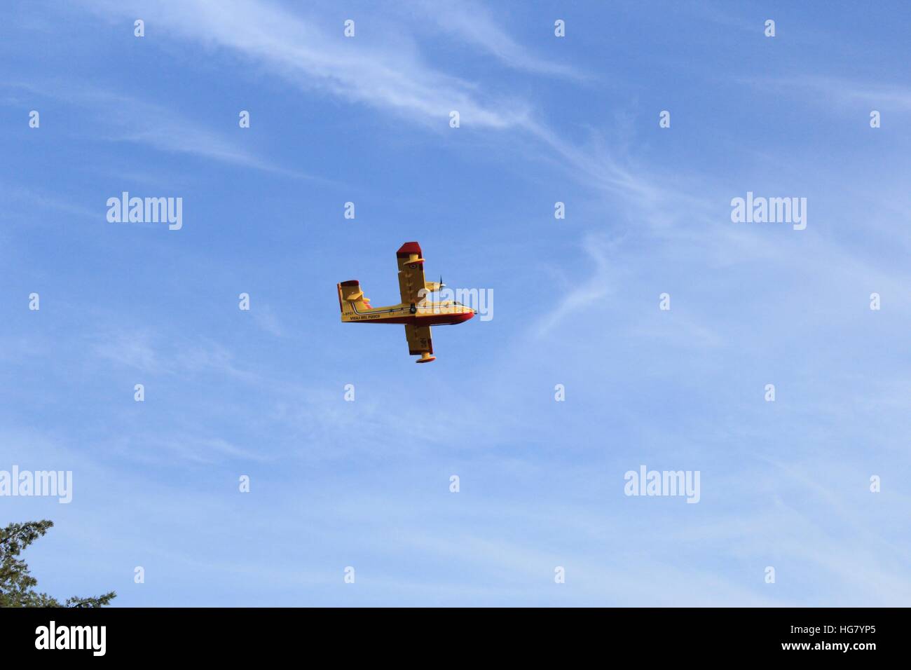 L'avion rouge et jaune de la Sicile Vigili del Fuoco monte dans un ciel bleu. Banque D'Images