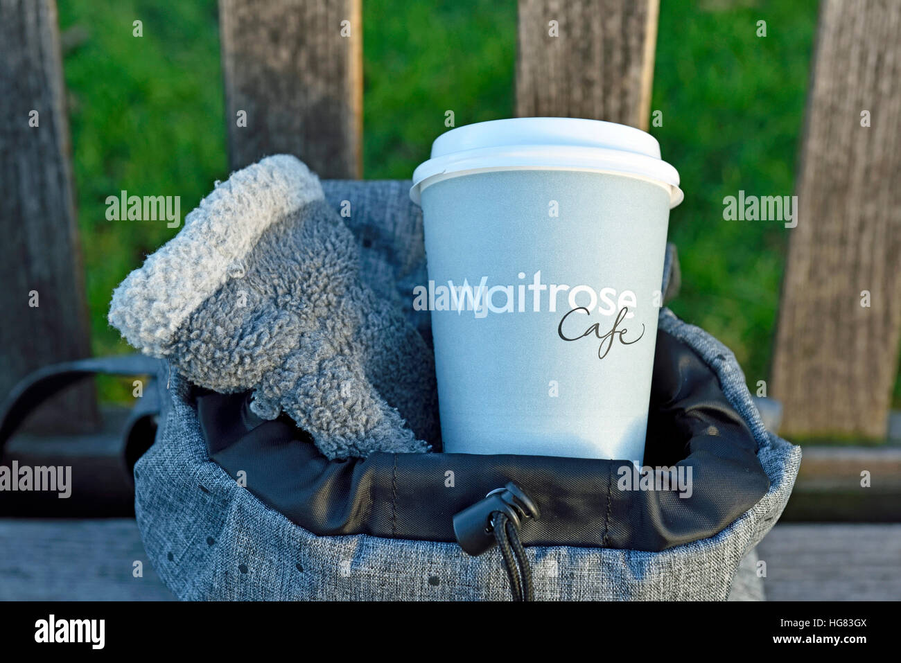 Waitrose emporter jetables dans la tasse de café avec sac à dos urbain gris smart glove sur banc froide journée d'hiver, le centre de Londres, Angleterre, RU Banque D'Images