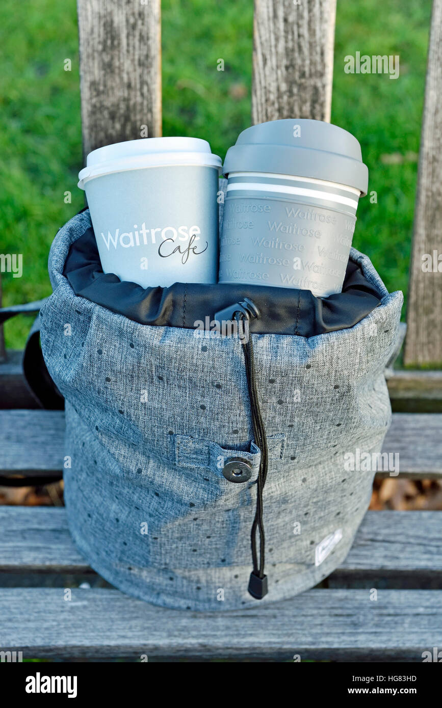 Waitrose emporter jetables et réutilisables tasse à café et tasse de voyage en sac à dos gris urbain intelligent sur banc de parc Central London Banque D'Images