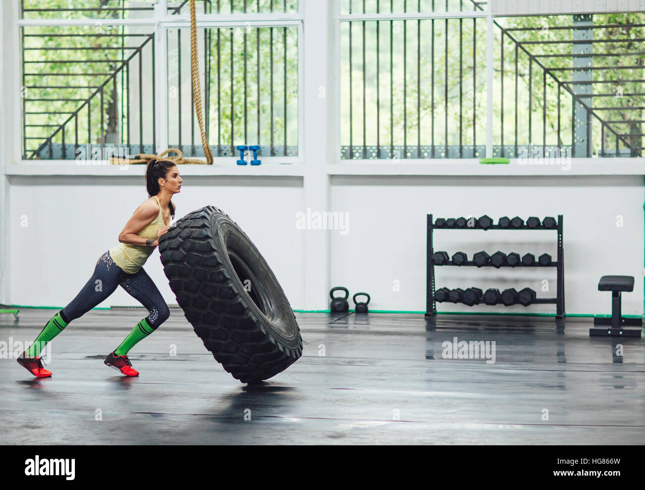 Vue latérale du sportif l'entraînement avec le pneu du tracteur en salle de sport Banque D'Images