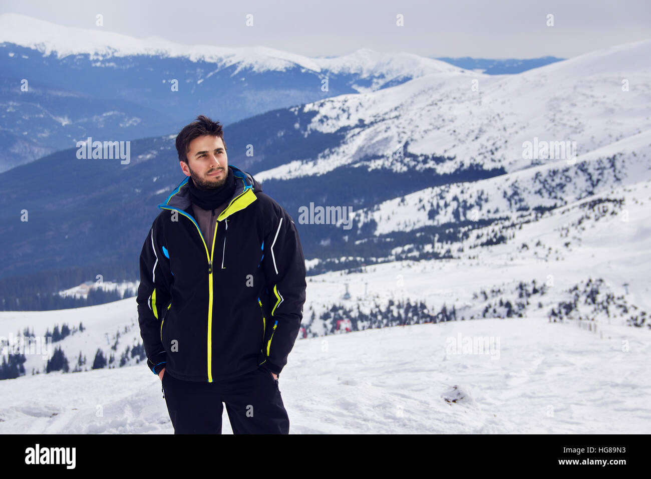 Un jeune homme debout sur une montagne enneigée Banque D'Images