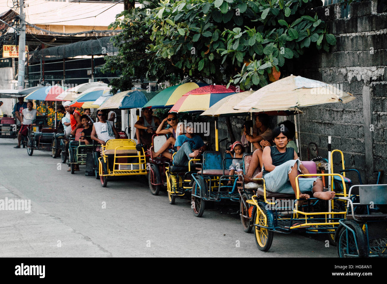 Les gens se détendre sur pedicab par mur en ville Banque D'Images