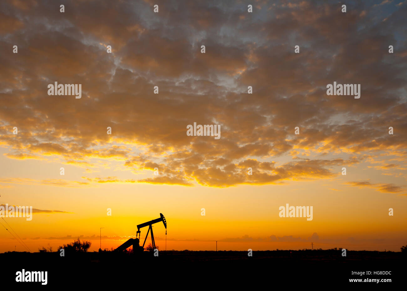 Pompe à huile Silhouette sur terrain contre ciel nuageux pendant le coucher du soleil Banque D'Images