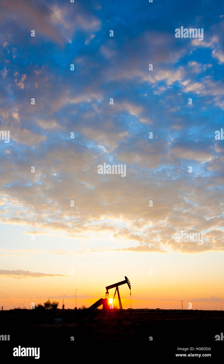 Pompe à huile sur field against cloudy sky pendant le coucher du soleil Banque D'Images