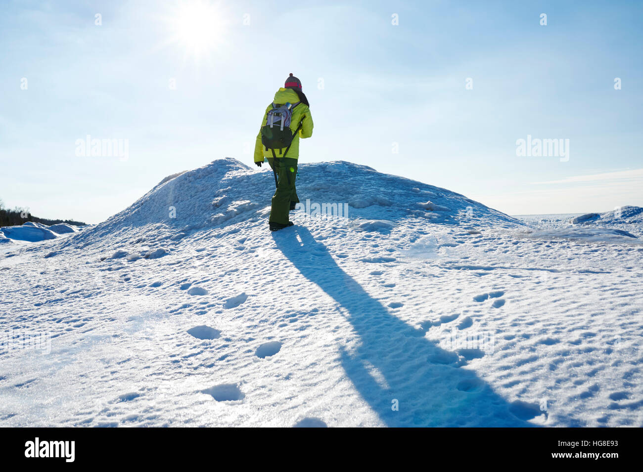 Vue arrière du female hiker walking on snow covered field against sky Banque D'Images