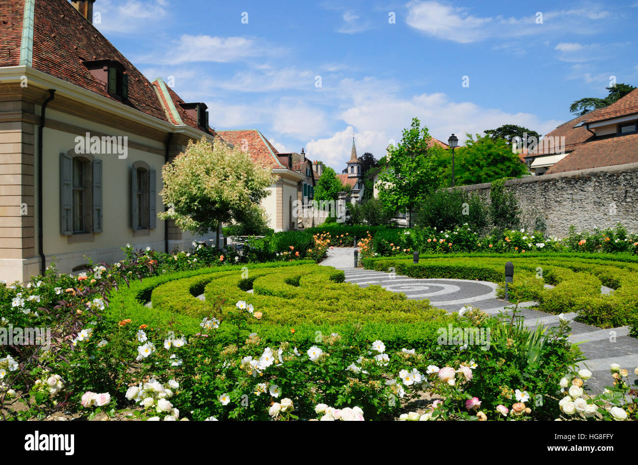 Jardins avec des fleurs et une vue sur l'église dans le centre du vieux village de Cologny Suisse. Banque D'Images