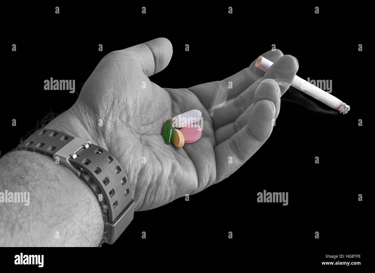 Une cigarette allumée dans la main avec des médicaments isolés - La cigarette est nuisible à la santé. Banque D'Images