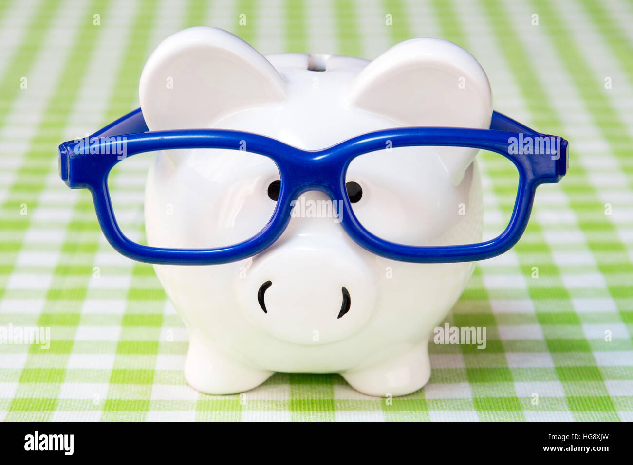 Tirelire avec lunettes bleu sur nappe à carreaux Banque D'Images