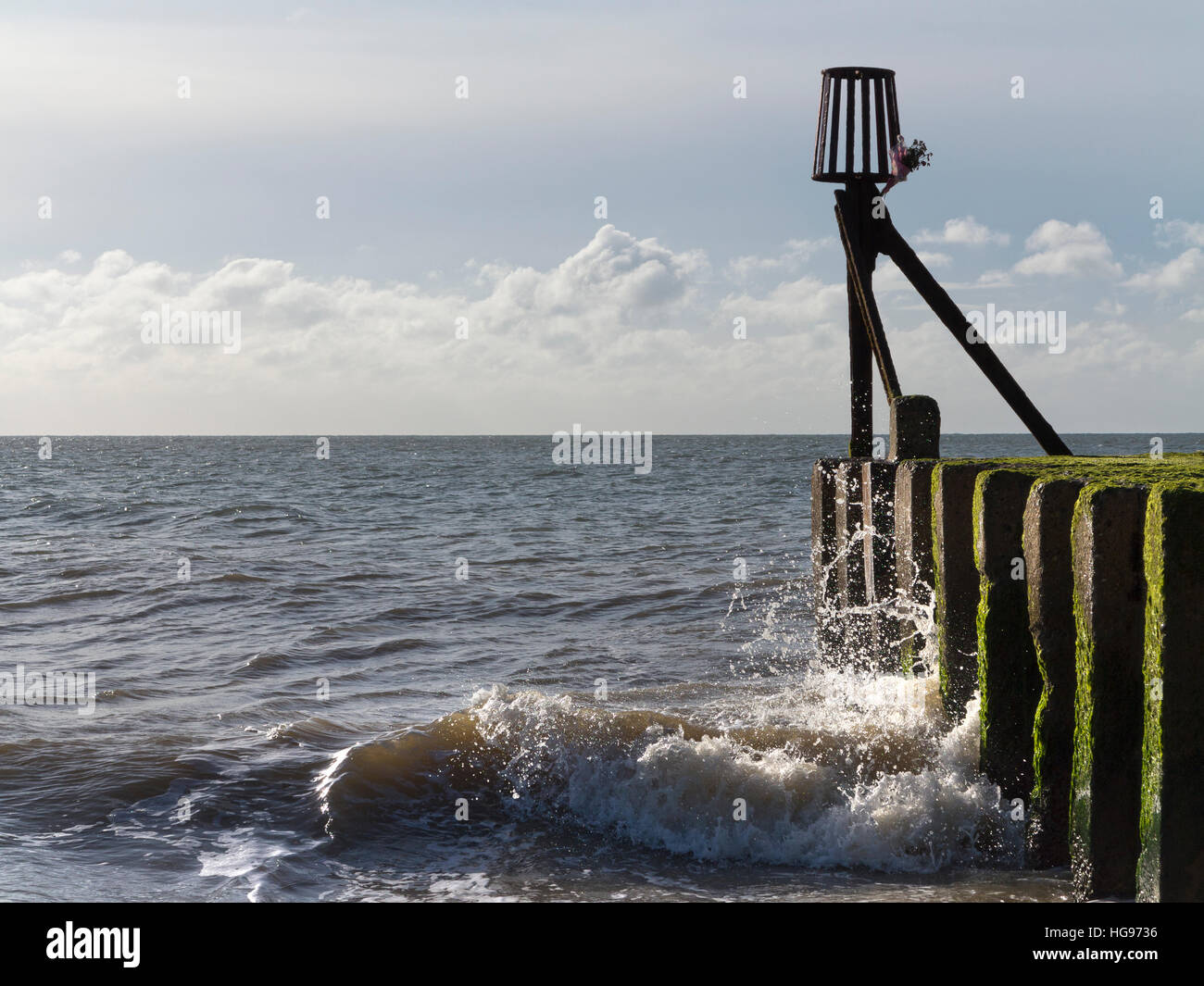 Vagues se brisant sur le rivage sur une aine avec un petit bouquet de fleurs séchées attaché à radiobornes fin Banque D'Images