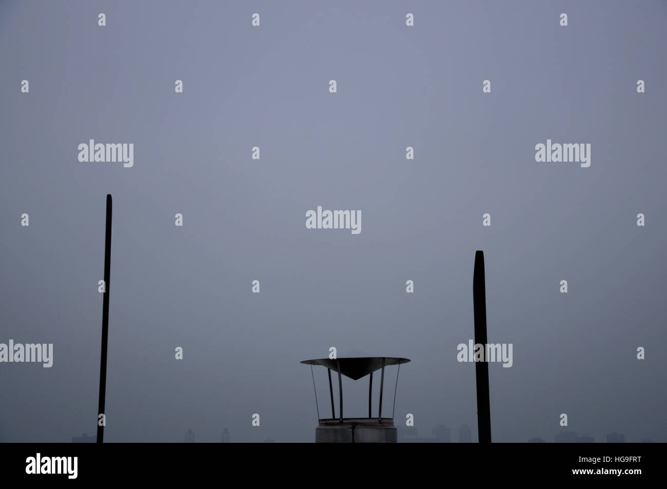 Vieux tuyaux de ventilation et avec un fond de ciel bleu-gris, les bâtiments visibles à l'horizon. Banque D'Images