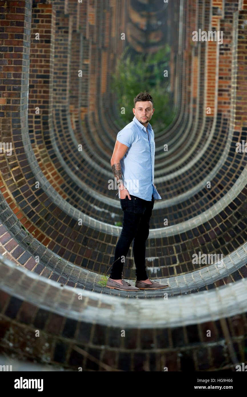 Chanteur, auteur-compositeur Jamie Mathias pose avec sa guitare pour un tournage à l'Ouse valley viaduc, Sussex, UK. Banque D'Images