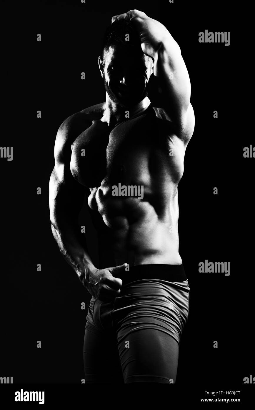 Portrait d'un jeune homme en bonne forme physique montrant son corps bien formé - Athletic musculaire Fitness Model Posing Bodybuilder Exercices après Banque D'Images