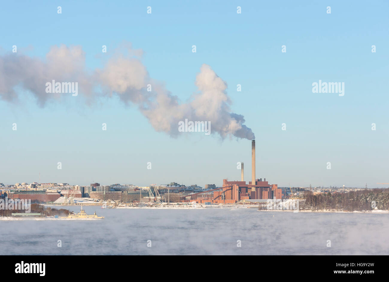 L'usine avec une grande cheminée fumer derrière l'eau d'hiver à vaporing Banque D'Images