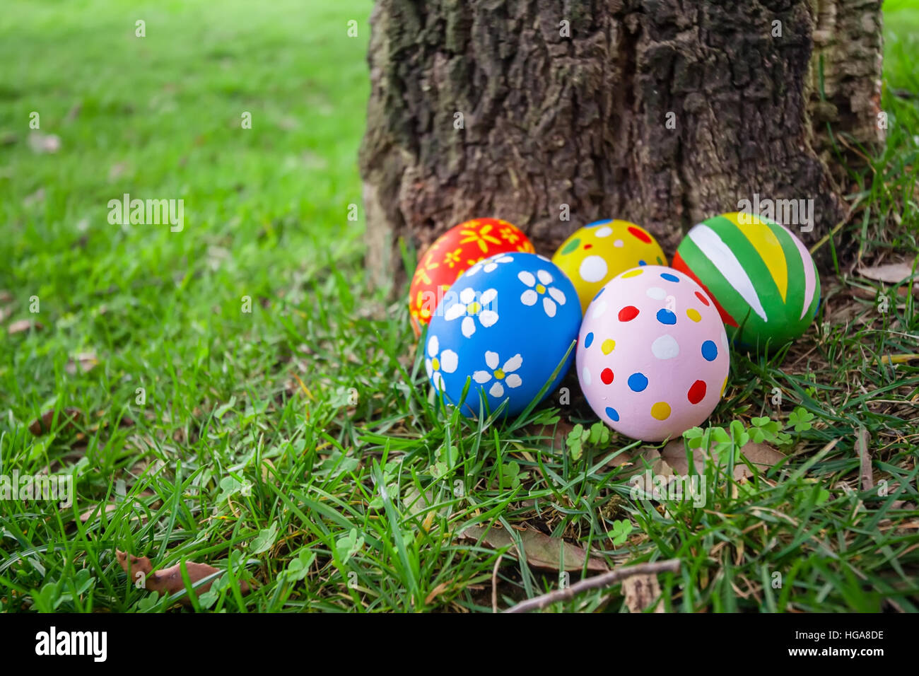 Les œufs de Pâques cachés derrière un tronc d'arbre pour la chasse jeu /// se cacher oeuf peint en vert prairie pelouse décorées appartement de vacances cadeau fête du printemps Banque D'Images