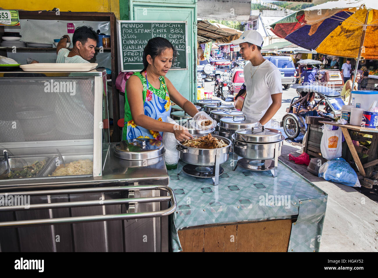 Une femme sert des plats de son restaurant trottoir aux Philippines. Banque D'Images