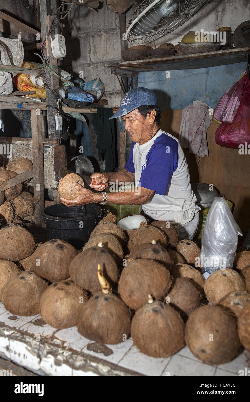 Un vieil homme de son pays se divise à son stand de coco du vendeur dans les Philippines. Banque D'Images