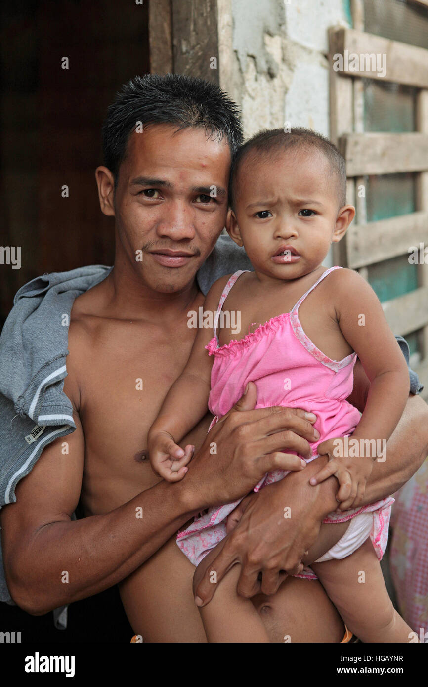 Portrait d'un jeune père philippin lui tenant sa petite fille à Roosevelt Ville, Province de Bataan, l'île de Luzon, aux Philippines. Banque D'Images