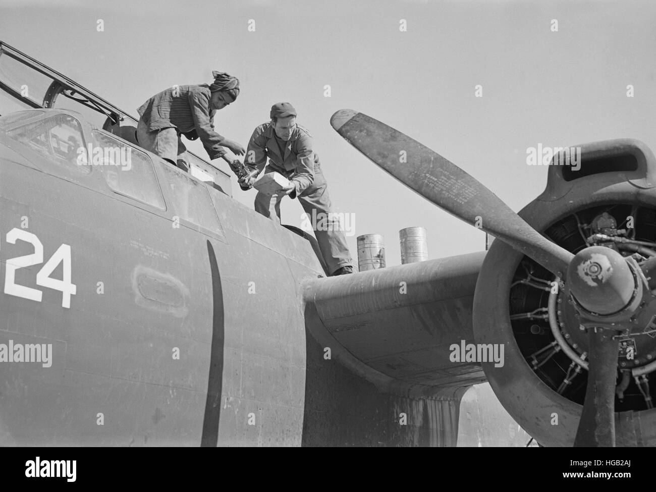 Un mécanicien d'avion américain assistée par un garçon iranien travaillant sur un bombardier léger, 1943. Banque D'Images