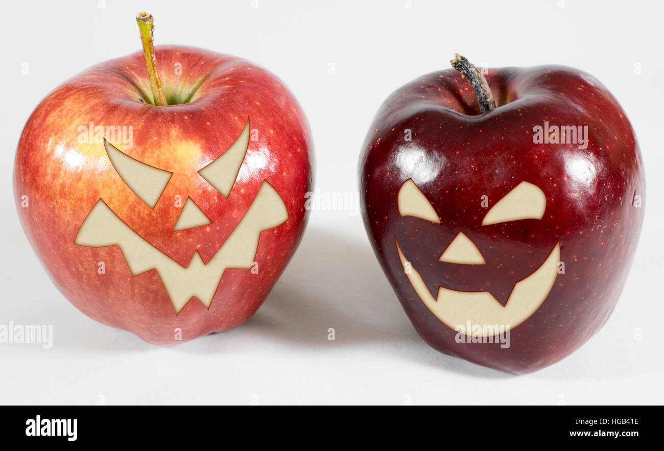2 pommes rouges avec drôle visages sculptés sur un fond blanc Banque D'Images