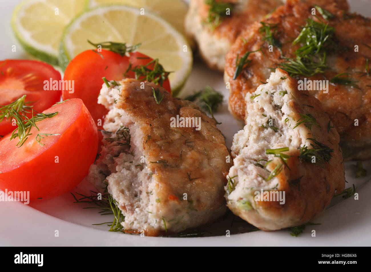 Gâteau de poisson frit avec des herbes macro sur une assiette blanche horizontale. Banque D'Images