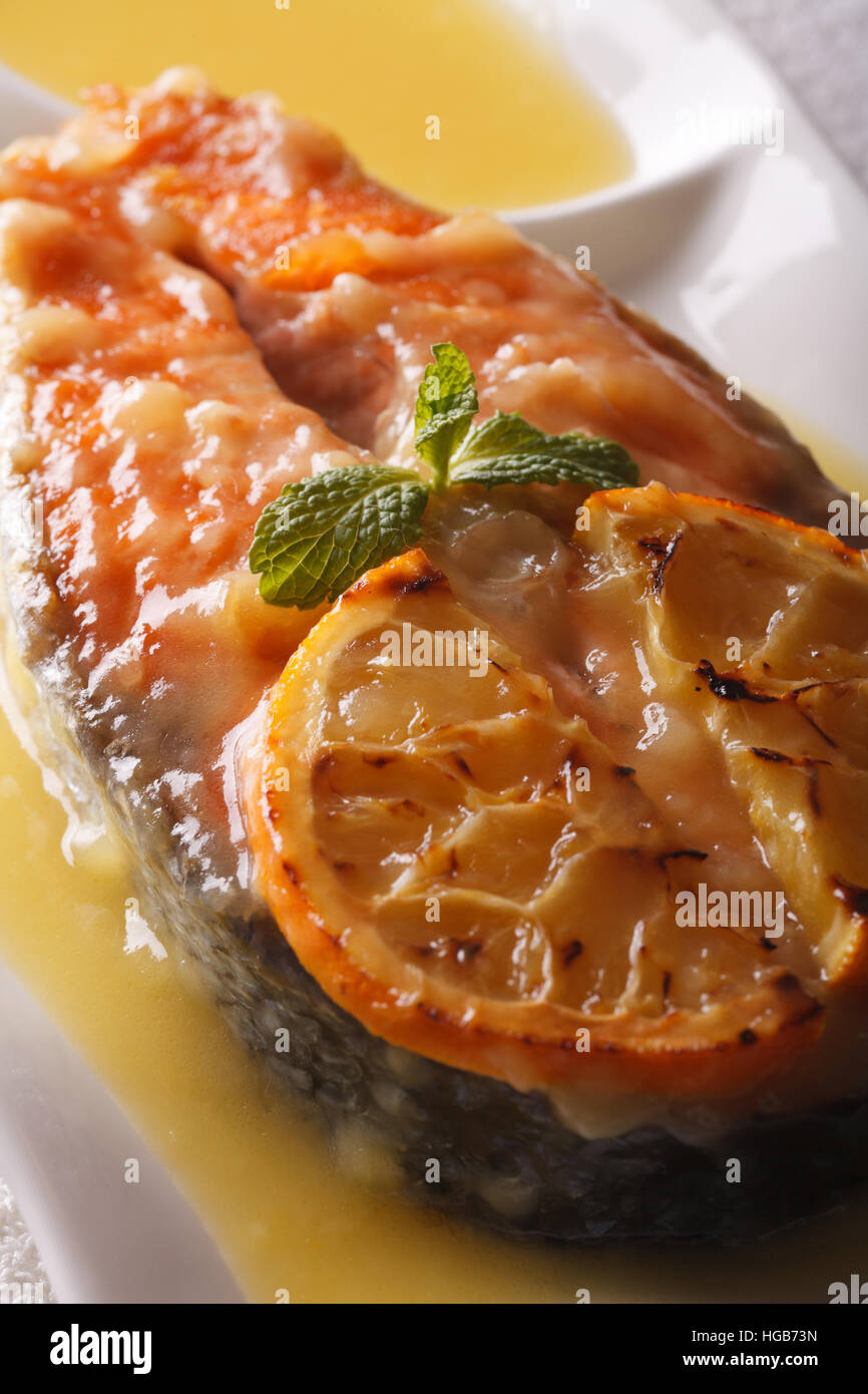 Saumon au four avec sauce à l'orange sur une plaque verticale macro. Banque D'Images