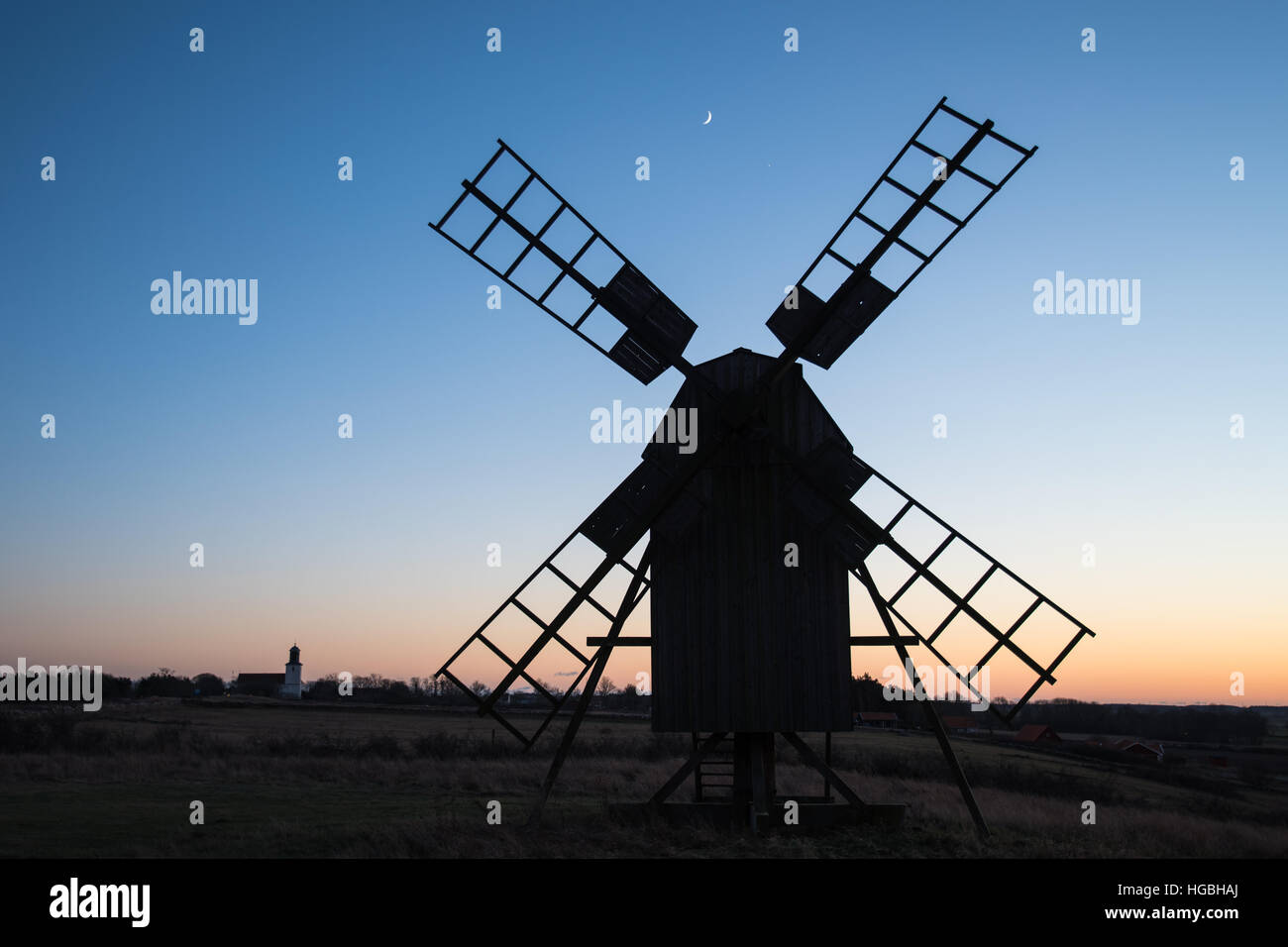 Paysage avec ancien moulin à vent en bois traditionnel et l'église silhouettes dans un village sur l'île suédoise Oland Banque D'Images