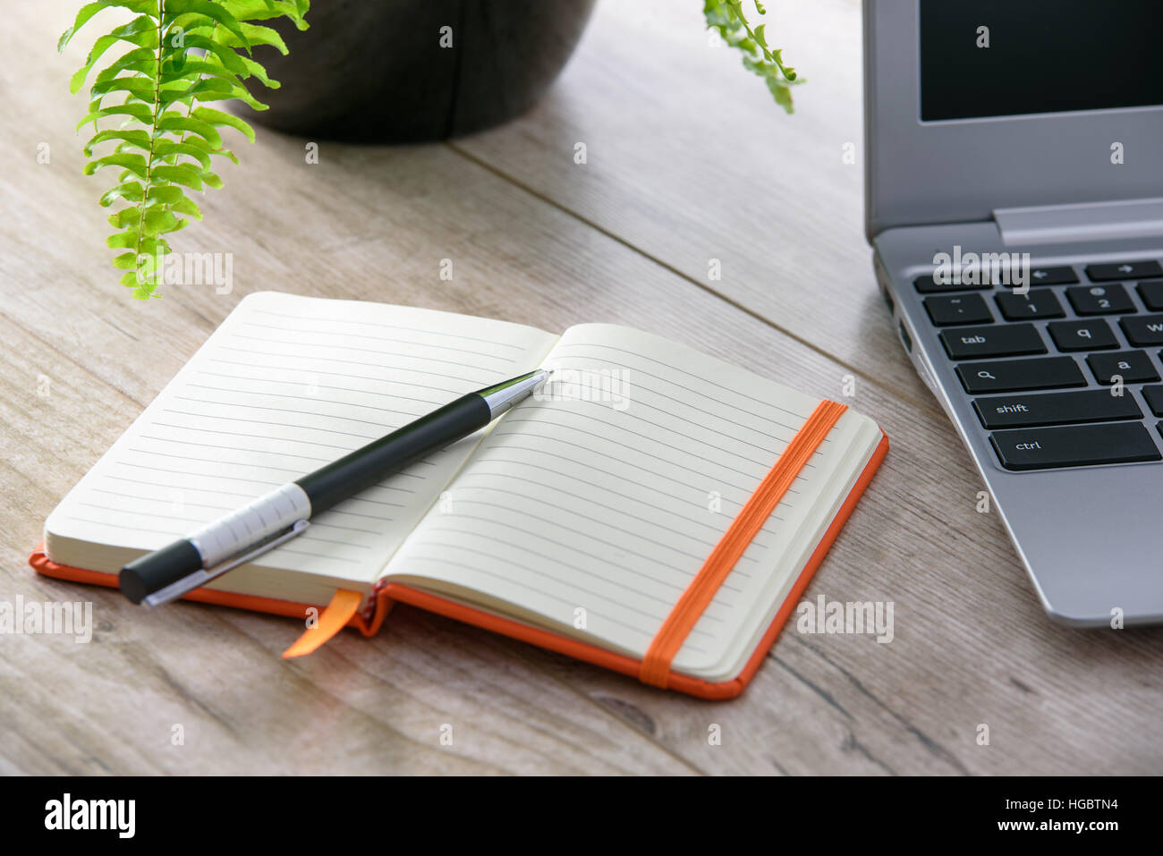 Peu féminin ordinateur portable sur une table en bois vintage à côté d'un ordinateur portable et de fleurs Banque D'Images