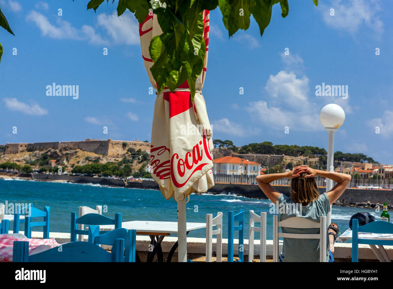Une femme assise dans un café donnant sur la mer Rethymno, Crète, Grèce Banque D'Images