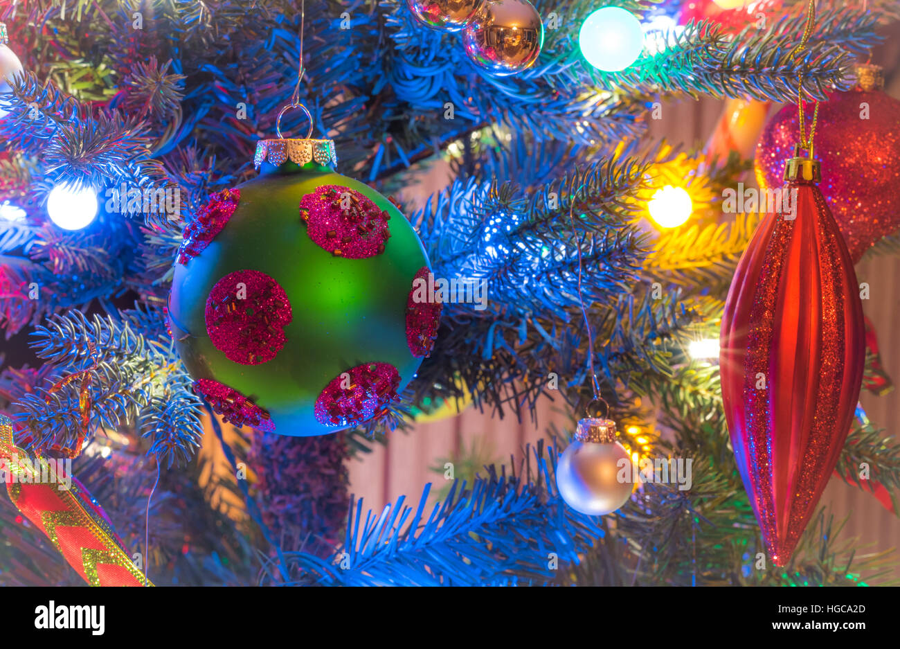 Décorations de Noël. Green, mat, l'orbe avec cercles magenta, les lueurs, entouré de lumières multicolores mini. Banque D'Images