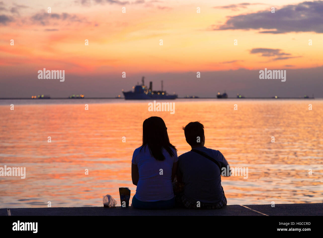 Filipino couple regardant le coucher du soleil, la baie de Manille, Philippines, Banque D'Images