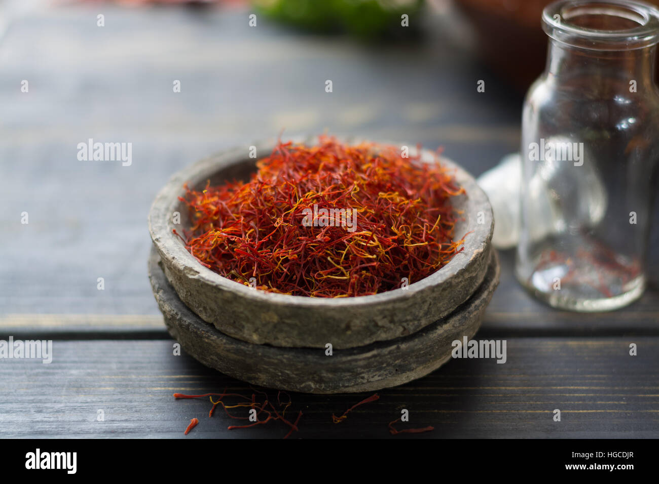Safran Rouge biologiques crus Spice dans une cuvette d'argile sur table en bois Banque D'Images