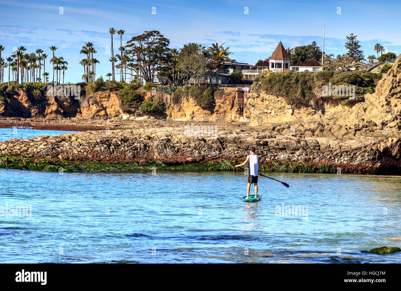 Paddleboarder sur une planche de surf sur l'océan comme il avirons de la plage sur la mer sur une journée ensoleillée. Banque D'Images