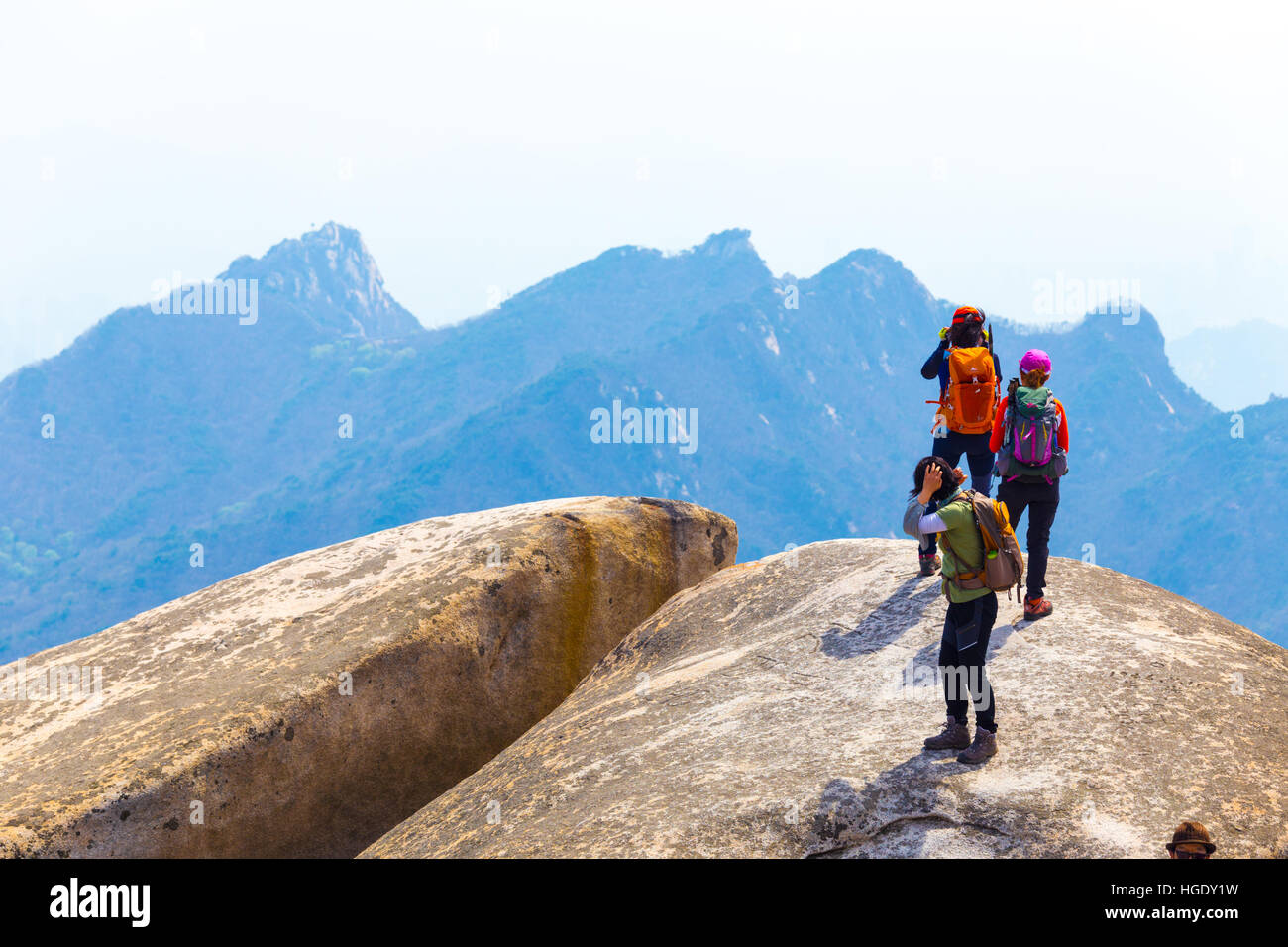 Trois femmes portant du matériel de randonnée colorés plein la vue sur les montagnes depuis pic de Bukhansan, Baegundae on a sunny day Banque D'Images