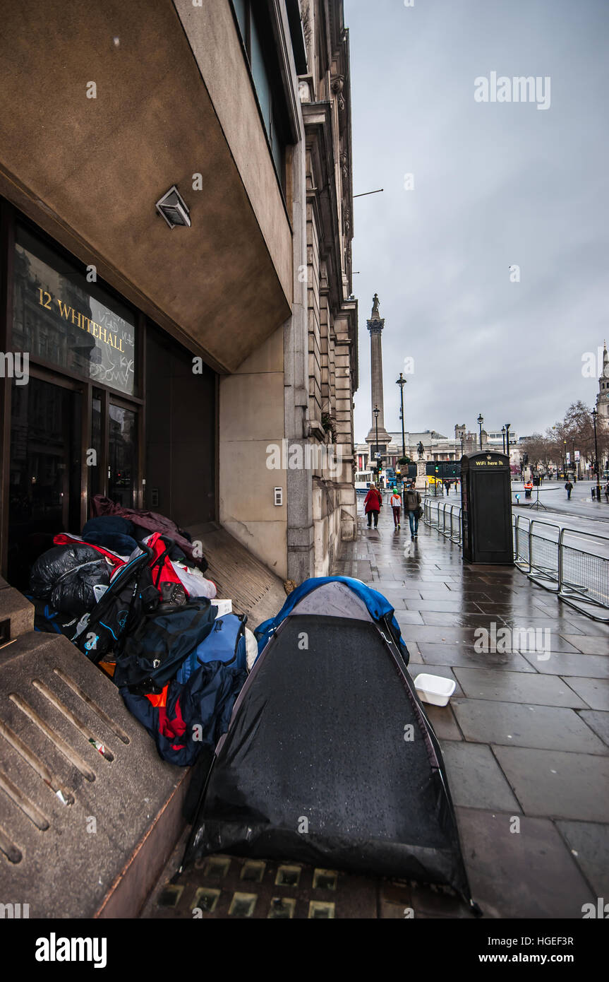 Un sans-abri campant à Whitehall, avec Trafalgar Square et Nelson Column Beyond. Mouillé par la pluie Banque D'Images