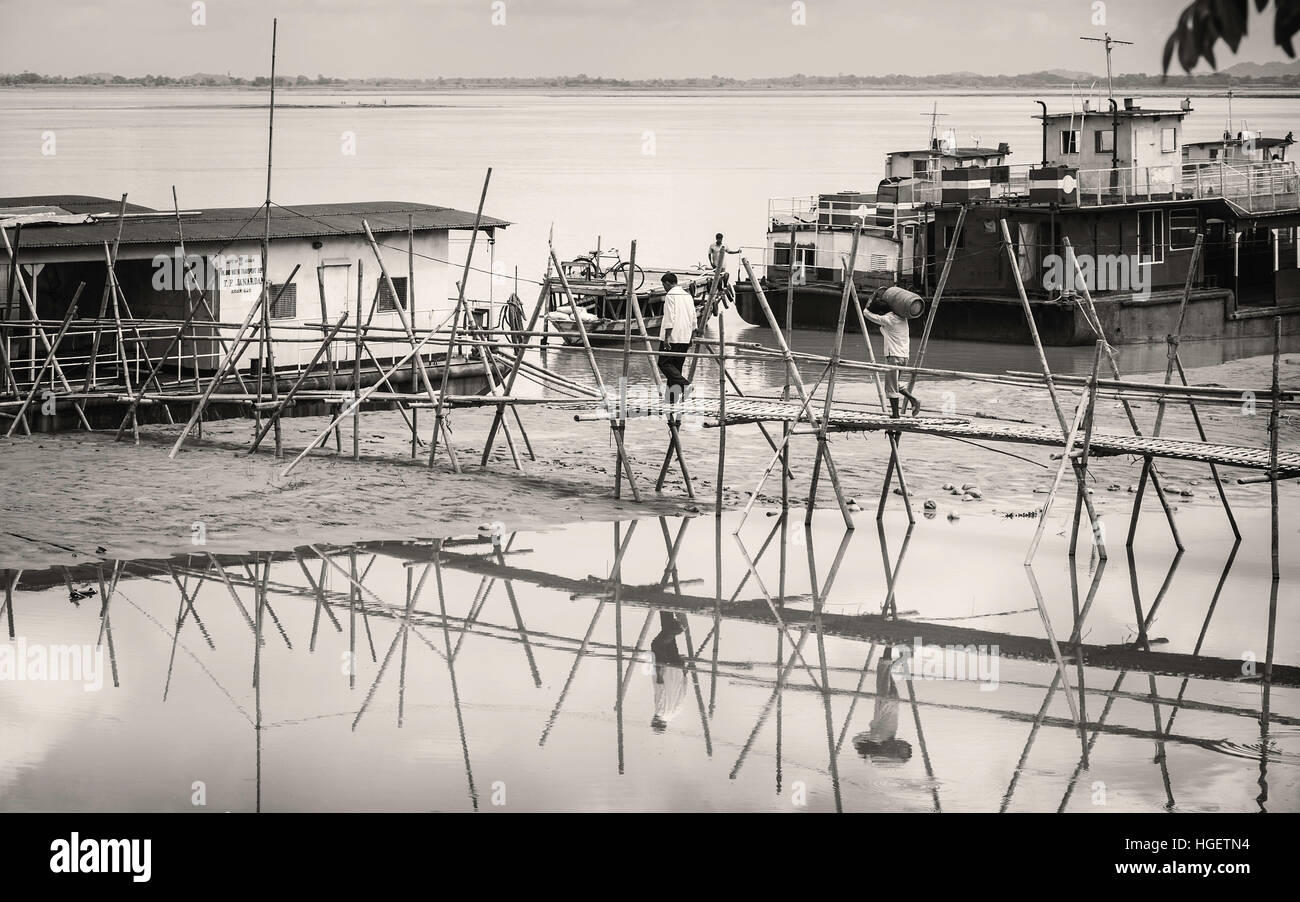 Les eaux de crue du Brahmapoutre reculer pour révéler bambou temporaire causeway entre rivière et de barges, de l'Assam. Banque D'Images
